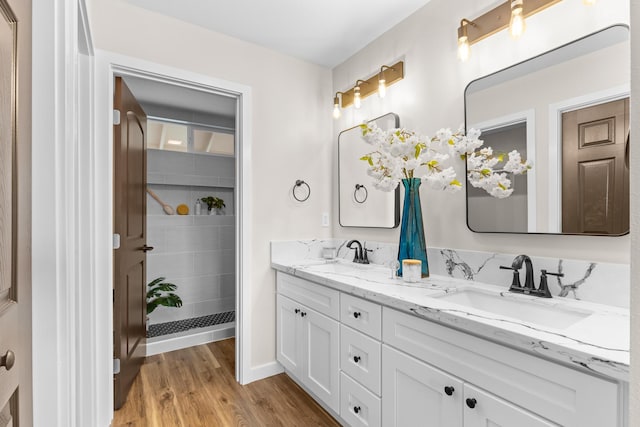 bathroom with hardwood / wood-style flooring, vanity, and a tile shower