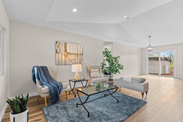 living area with an inviting chandelier, vaulted ceiling, and light wood-type flooring