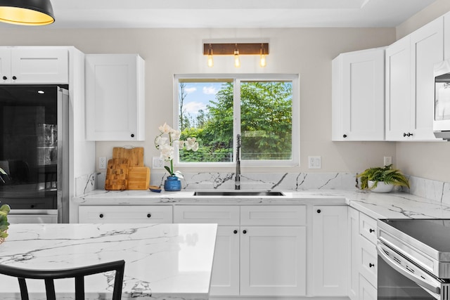 kitchen with black refrigerator, white cabinetry, sink, light stone countertops, and electric stove