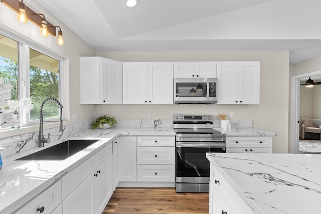 kitchen featuring sink, white cabinetry, vaulted ceiling, stainless steel appliances, and light hardwood / wood-style floors