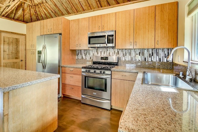 kitchen with appliances with stainless steel finishes, sink, tasteful backsplash, and light stone countertops