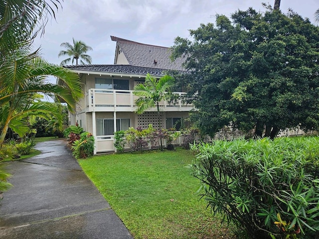 view of front of property featuring a balcony and a front yard