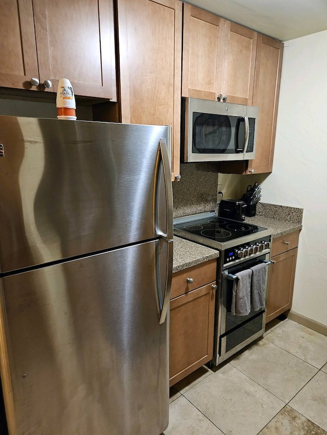 kitchen with appliances with stainless steel finishes, light tile patterned floors, and backsplash