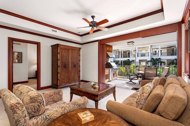 living room with light colored carpet, ornamental molding, a raised ceiling, and ceiling fan