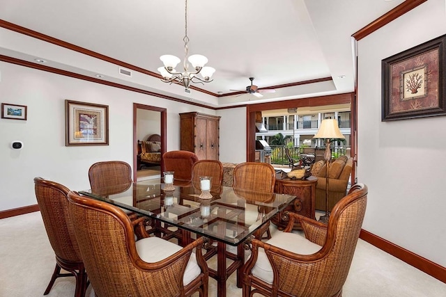 carpeted dining space featuring a tray ceiling, ceiling fan with notable chandelier, and ornamental molding