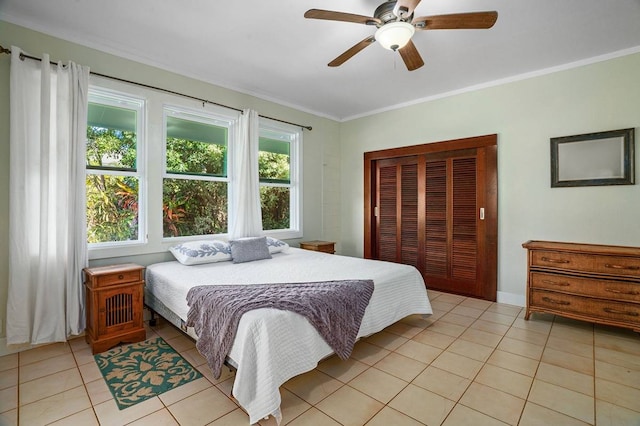 tiled bedroom with ceiling fan, ornamental molding, and a closet