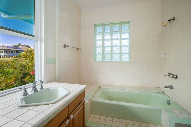 bathroom featuring a healthy amount of sunlight, tiled shower / bath combo, and vanity