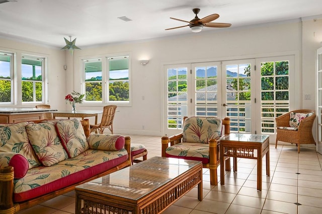 tiled living room with crown molding, french doors, ceiling fan, and a wealth of natural light