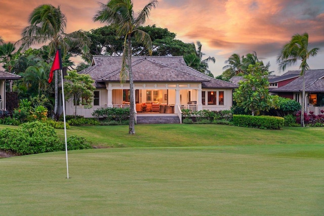 back house at dusk featuring a yard