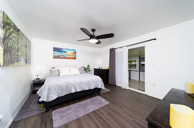 bedroom with ceiling fan, a textured ceiling, and dark wood-type flooring