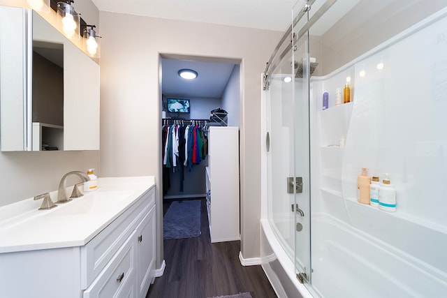 bathroom with hardwood / wood-style floors, vanity, and combined bath / shower with glass door