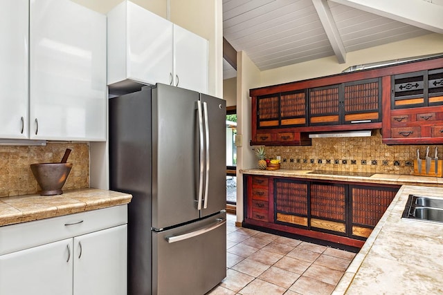 kitchen featuring stainless steel refrigerator, white cabinetry, backsplash, black electric cooktop, and light tile patterned floors