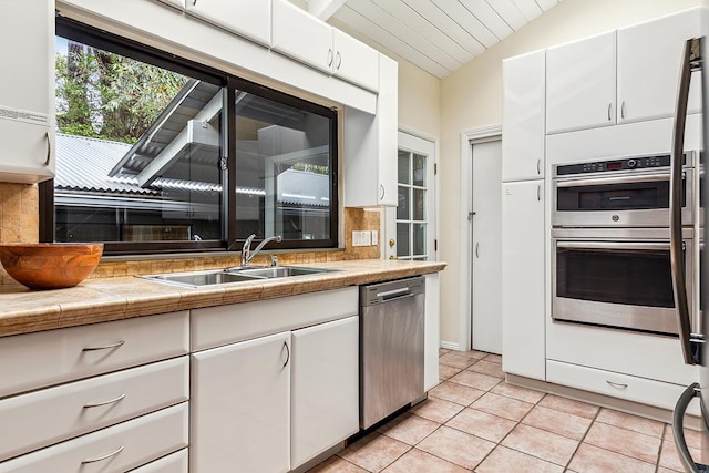 kitchen with white cabinets, lofted ceiling, sink, and appliances with stainless steel finishes