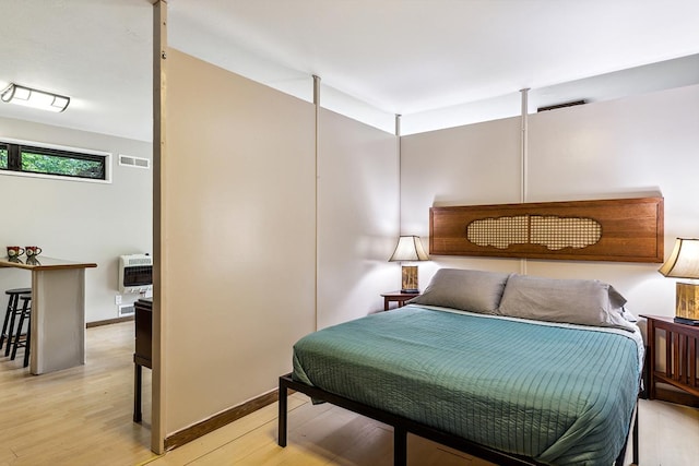 bedroom with heating unit and light hardwood / wood-style flooring