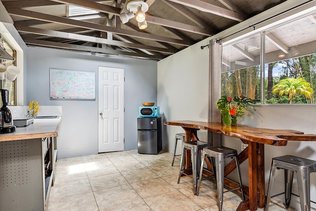 kitchen featuring vaulted ceiling, light tile patterned floors, wood ceiling, and fridge