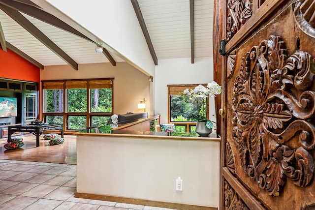 interior space featuring vaulted ceiling with beams and light tile patterned flooring