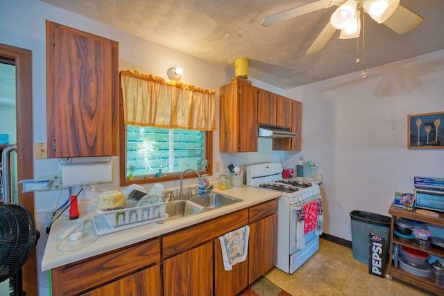 kitchen featuring white gas range oven, ceiling fan, sink, and light tile flooring