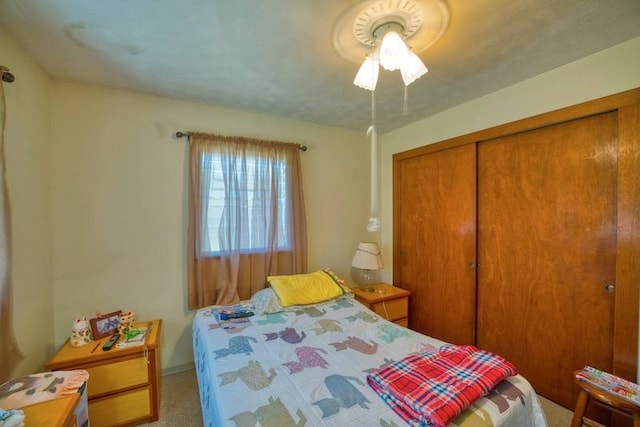 carpeted bedroom featuring ceiling fan and a closet