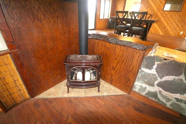 interior details featuring wooden walls, a wood stove, and wood-type flooring