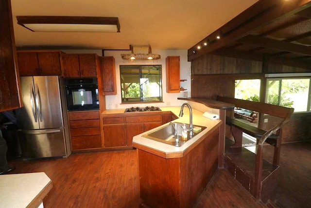 kitchen with appliances with stainless steel finishes, sink, kitchen peninsula, and dark wood-type flooring