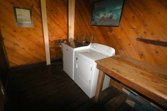 clothes washing area featuring washer and dryer, wood walls, and dark hardwood / wood-style flooring