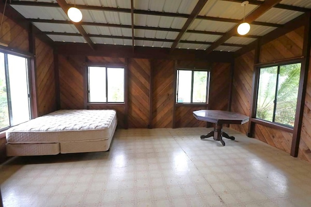 tiled bedroom featuring wood walls and multiple windows