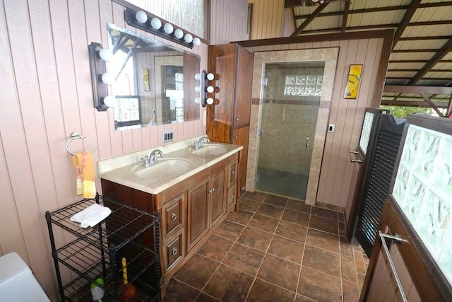 bathroom featuring wood walls, oversized vanity, walk in shower, dual sinks, and tile flooring