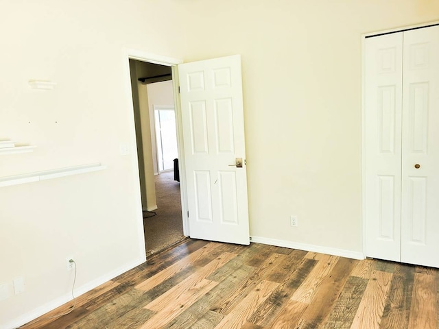 unfurnished bedroom with a closet and dark hardwood / wood-style flooring