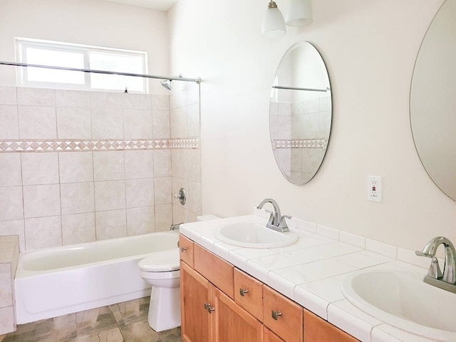 full bathroom featuring toilet, dual bowl vanity, tile flooring, and tiled shower / bath combo