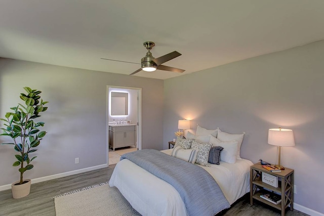 bedroom featuring dark hardwood / wood-style flooring, ceiling fan, connected bathroom, and sink