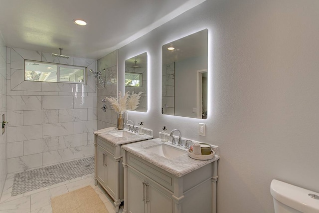 bathroom featuring toilet, vanity, tiled shower, and tile flooring