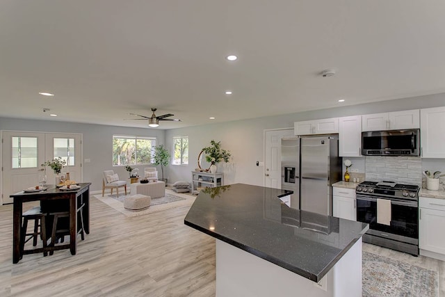 kitchen with a kitchen island, white cabinetry, light hardwood / wood-style floors, and appliances with stainless steel finishes