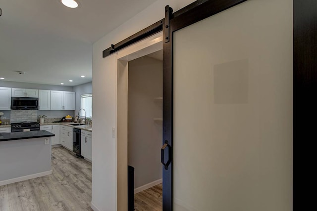 interior space with a barn door, sink, and light hardwood / wood-style flooring