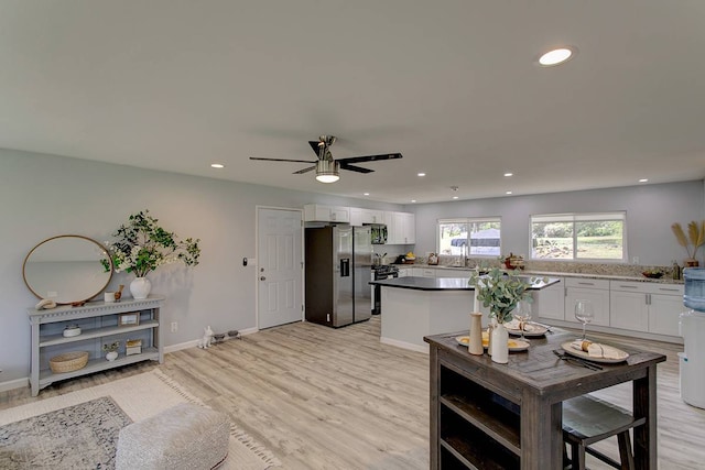 living room featuring ceiling fan, sink, and light hardwood / wood-style floors