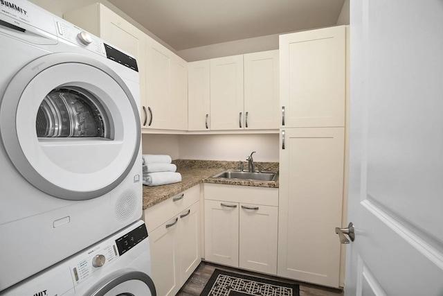 laundry room featuring stacked washer / dryer, cabinets, and sink