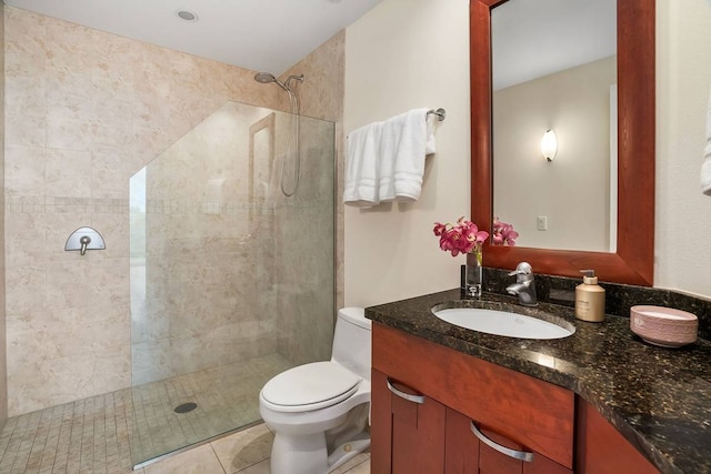 bathroom with toilet, tile flooring, a tile shower, and vanity