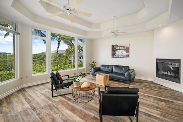 living room featuring a raised ceiling, light hardwood / wood-style floors, and ceiling fan