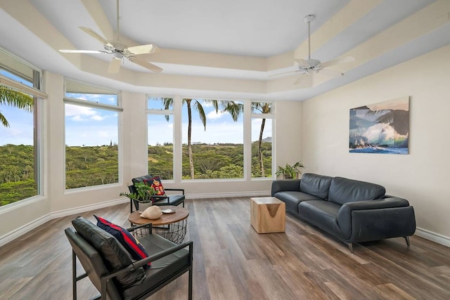 living room with ceiling fan, a raised ceiling, and dark hardwood / wood-style flooring