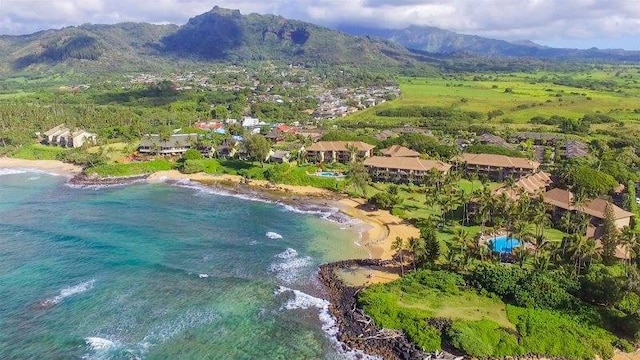 drone / aerial view with a water and mountain view and a view of the beach