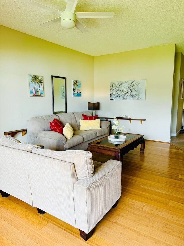 living room featuring light hardwood / wood-style floors, ceiling fan, and a textured ceiling