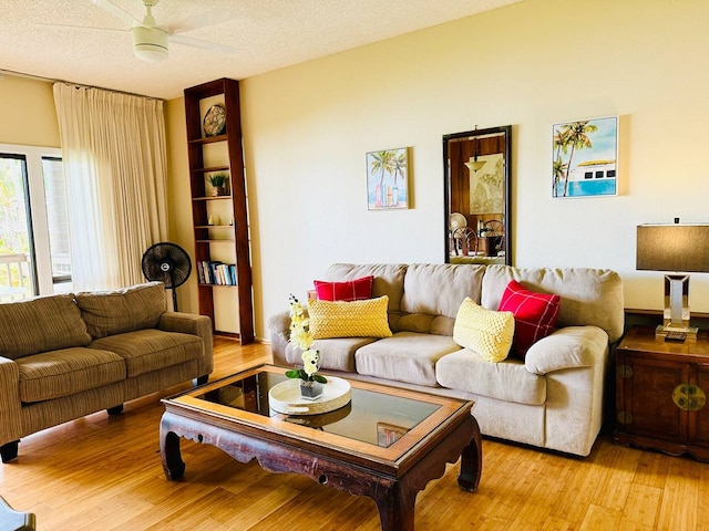 living room featuring a textured ceiling, ceiling fan, and light hardwood / wood-style flooring