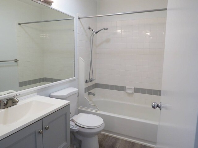 full bathroom with tiled shower / bath combo, toilet, hardwood / wood-style flooring, and oversized vanity