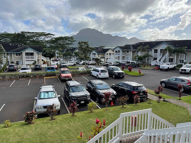 view of parking with a lawn and a mountain view