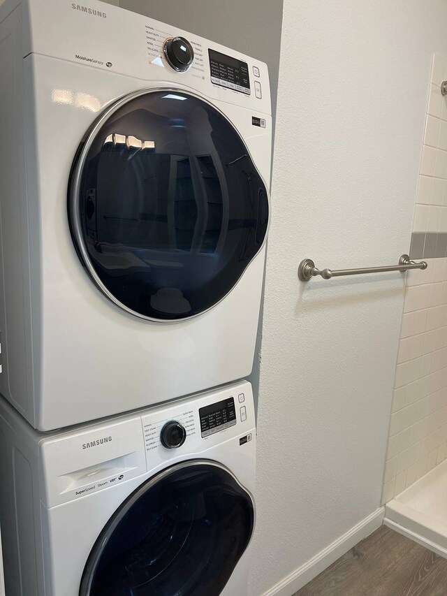 clothes washing area with dark hardwood / wood-style flooring and stacked washer and dryer