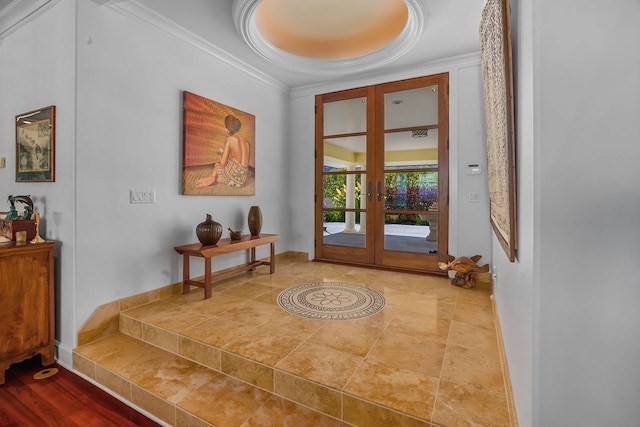 interior space with ornamental molding, a raised ceiling, light hardwood / wood-style floors, and french doors