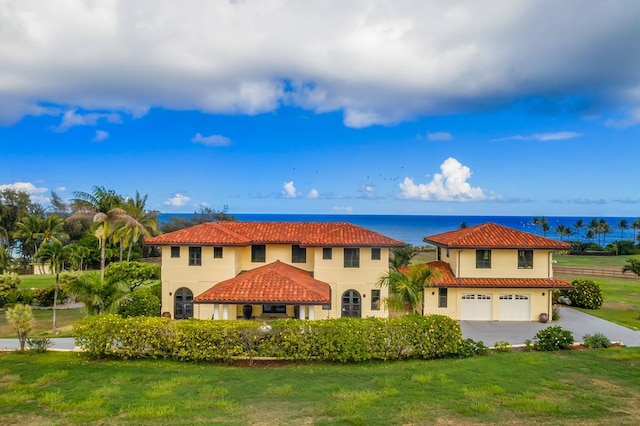 mediterranean / spanish-style house with a front yard, a water view, and a garage