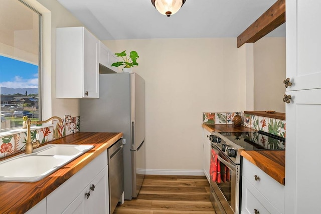 kitchen with white cabinets, light wood-type flooring, wood counters, and appliances with stainless steel finishes