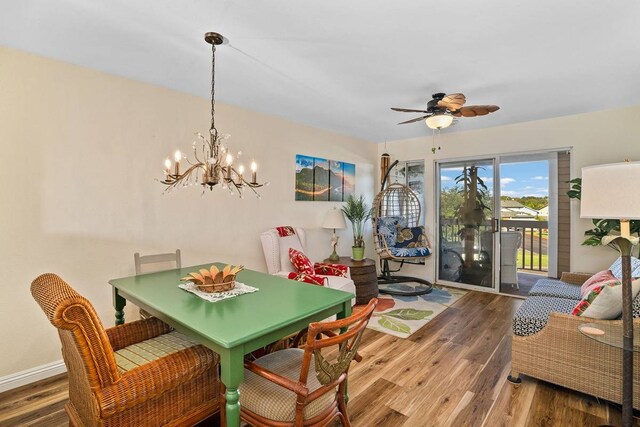 dining area with dark hardwood / wood-style flooring and ceiling fan with notable chandelier