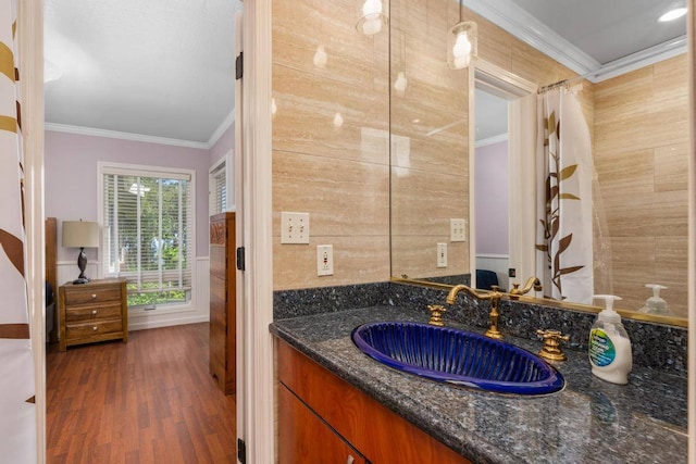 bathroom featuring hardwood / wood-style flooring, tile walls, ornamental molding, and vanity