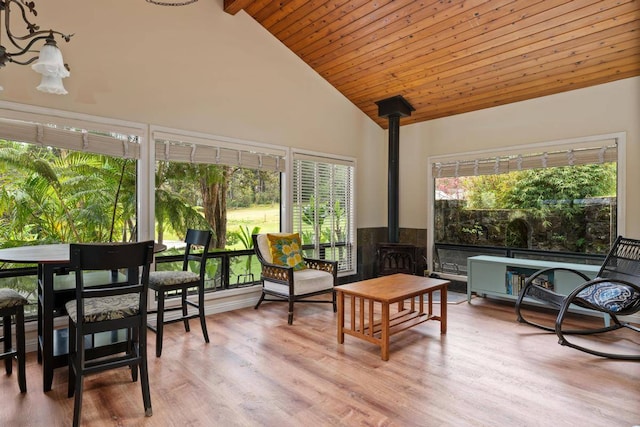 sunroom with wooden ceiling, vaulted ceiling, and a wood stove